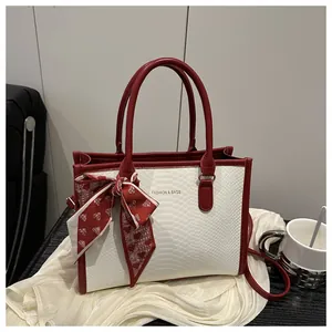 Close-up of red and white snakeskin tote bag featuring fashion text and silk scarf bow