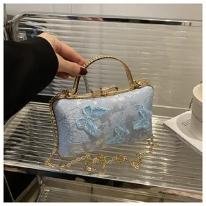 Detail of light blue satin evening bag with butterfly embroidery and crystal handle