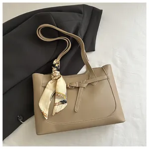 Détail du sac cabas kaki avec un foulard en soie à motif vintage noué sur l'anse