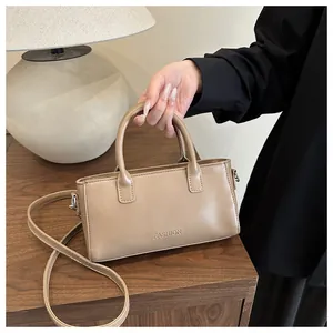 Dettaglio borsa a mano beige in pelle con finiture argento su tavolo di legno