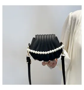Détail d'un sac coquillage noir avec texture plissée et poignée en perles blanches