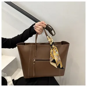Detail of dark brown faux leather tote bag with silk scarf and white contrast stitching