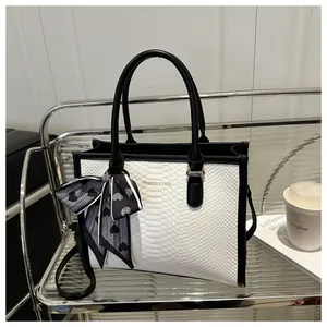 Detail of snake pattern contrast handbag with silk scarf on a stylish display shelf
