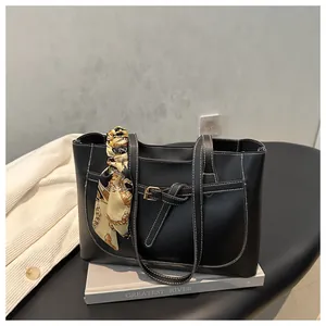 Détail du sac cabas noir avec surpiqûres blanches, boucle dorée et foulard en soie