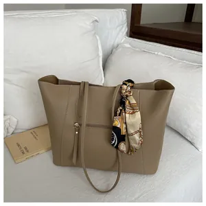 Close-up of khaki tote bag featuring premium leather texture and elegant silk scarf detail