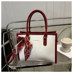 Close-up of stylish faux snake skin tote bag with red leather trim and silk scarf detail