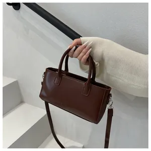 Dettaglio della borsa in ecopelle marrone scuro con finitura lucida e scritta moda