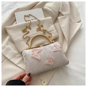 Detailed macro view of ivory lace clutch with 3D pink butterflies and gold top handle