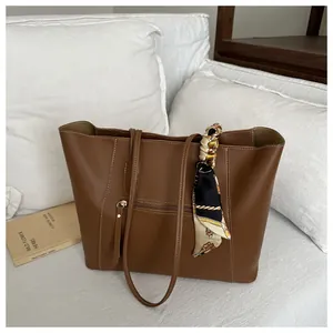 Close-up of brown PU leather tote bag with decorative silk scarf and front zipper pocket