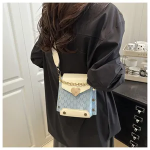 Detail showing contrast blue and white PU leather bag with heart clasp and wide strap