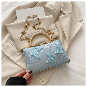 Detailed embroidery of 3D butterflies on a light blue handbag with golden metal handle