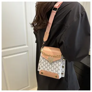 Detail of crossbody bag with M-letter print, heart buckle and pink wide strap