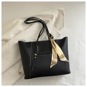 Detail of black tote bag with white stitching and decorative printed silk scarf on handle