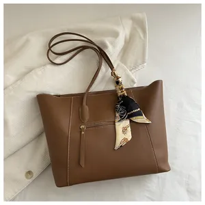 Detail of brown leather tote bag featuring white contrast stitching and floral silk scarf