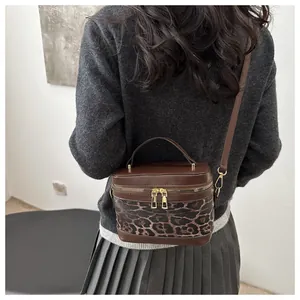 Vue détaillée du sac bandoulière léopard avec double fermeture éclair dorée et poignée marron