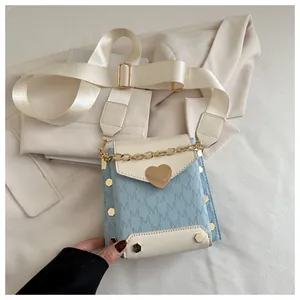Close-up of color-block crossbody bag with heart clasp and textured jacquard pattern