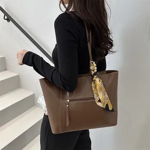 Dark brown leather tote bag with decorative silk scarf and front zipper pocket