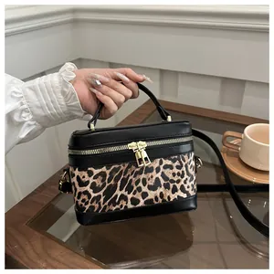 Détail du sac boîte léopard avec fermetures dorées et finitions en cuir noir