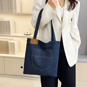 Large dark blue denim tote bag with front pocket shown in a lifestyle indoor setting