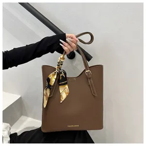 Détail d'un grand sac cabas marron avec foulard décoratif et logo doré élégant