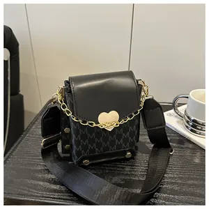 Detail of black crossbody bag with M-letter print, gold heart buckle and wide strap