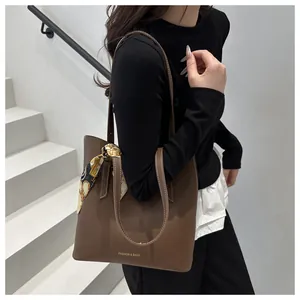 Détail du sac fourre-tout en cuir mat marron foncé avec foulard en soie imprimé