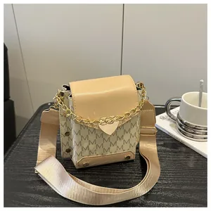 Detail of contrast stitch flap bag with letter monogram pattern and gold chain heart charm