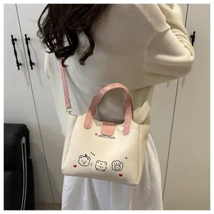 Détail d'un sac cabas crème avec poignées roses et imprimé ours porté par un mannequin