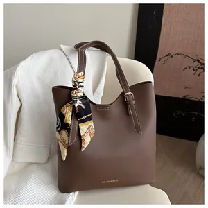 Détail du sac cabas marron foncé avec texture grainée et foulard en soie sur la poignée