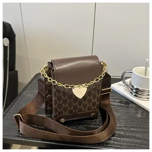 Detailed macro of vintage monogram crossbody bag with heart pendant and rivet details