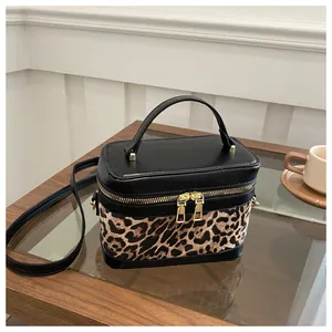 Détail du sac léopard montrant les fermetures dorées et la poignée en cuir noir