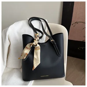 Détail du sac cabas noir avec lettrage doré et un foulard en soie noué sur la bandoulière