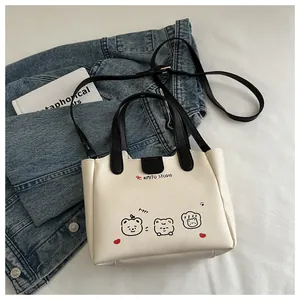 Détail du sac fourre-tout crème avec imprimés chiots et bandoulière noire amovible