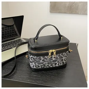 Détail du sac léopard avec double fermeture éclair dorée et finitions en cuir