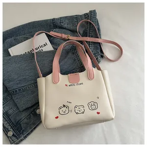 Détail d'un sac cabas crème avec poignées roses et motif animalier sur denim