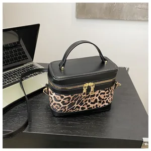 Détail des fermetures éclair doubles et du motif léopard sur le sac boîte en cuir