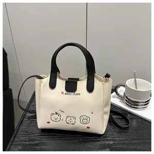 Détail du sac cabas crème avec oursons de dessin animé et poignées noires contrastées