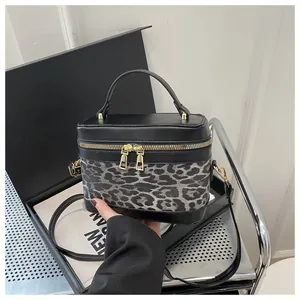 Détail du sac boîte léopard avec couvercle en cuir noir et zips métalliques dorés
