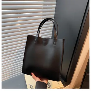 Detail view of smooth black faux leather tote with round magnetic buckle closure