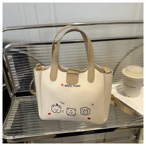Gros plan du sac cabas crème avec illustrations de chiots et détails de poignée kaki