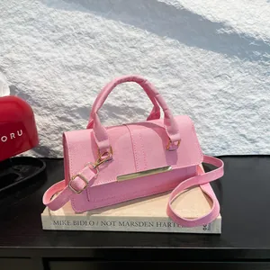 Sac à main rose en sergé avec détails dorés et bandoulière sur des livres