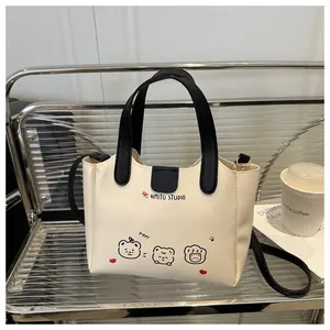 Détail du sac fourre-tout crème avec imprimé chiot et poignées en cuir noir