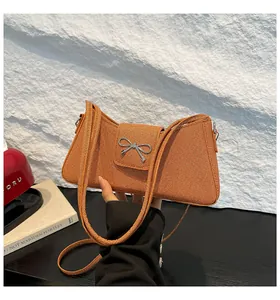 Détail du sac baguette orange tressé avec boucle argentée et bandoulière chic