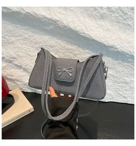 Vue détaillée du sac baguette en tissu gris avec une boucle en métal argenté en nœud