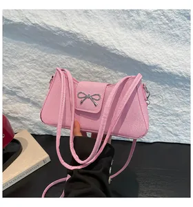 Détail de la texture en sergé rose et du nœud en métal argenté sur un sac baguette tendance
