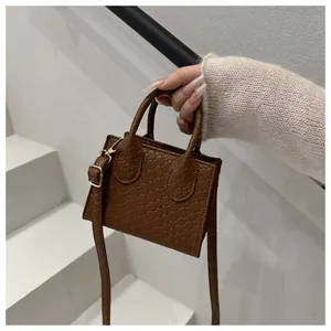 Detail of a brown woven mini tote bag featuring textured PU leather and gold hardware