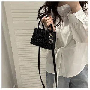 Detail of a black woven mini handbag featuring a detachable strap and gold metal hardware
