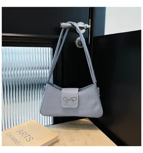 Détail du sac bandoulière gris en tissu avec boucle nœud sur une poignée de porte