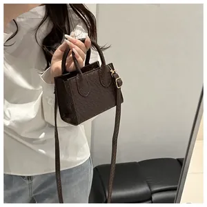 Close-up of dark brown crocodile embossed mini tote with golden metal hardware detail