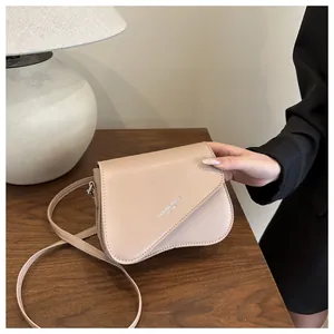 Detail of minimalist beige crossbody bag with curved flap and Fashion Trend 1996 text